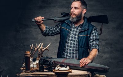 Bearded modernl hunter with his trophy holds a rifle.