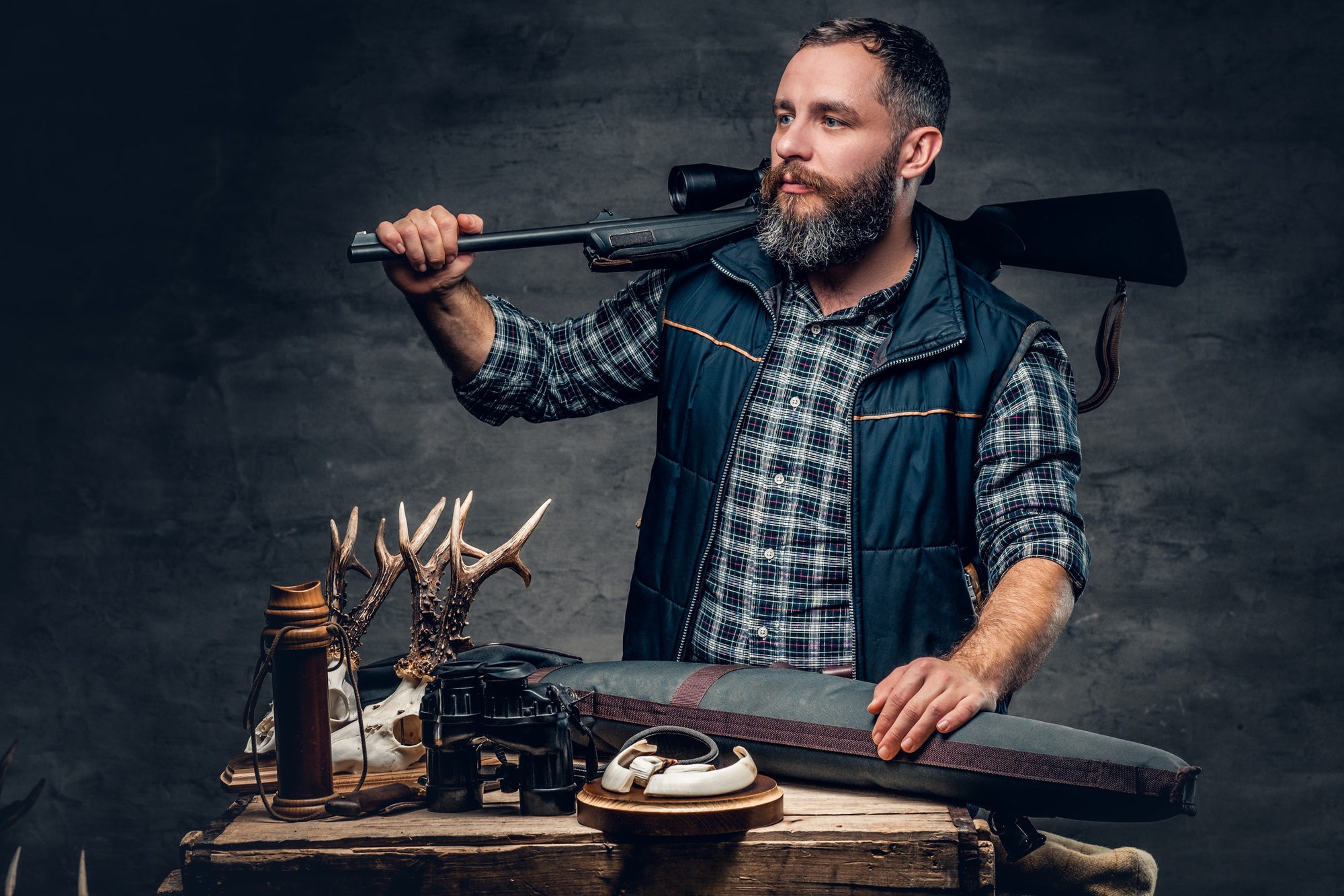 Bearded modernl hunter with his trophy holds a rifle.