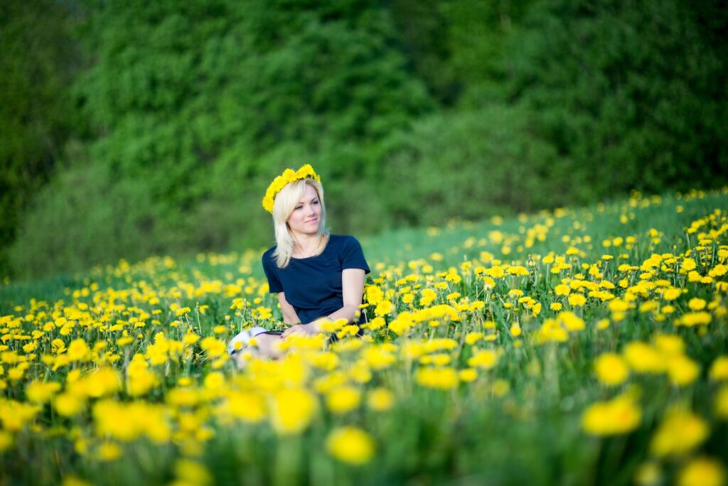 A beautiful young woman is relaxing in the flowering dandelion meadow