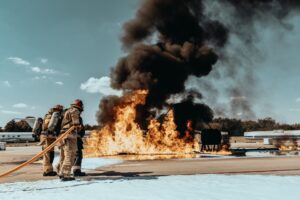 Firefighters extinguishing a large fire at an airport training facility.